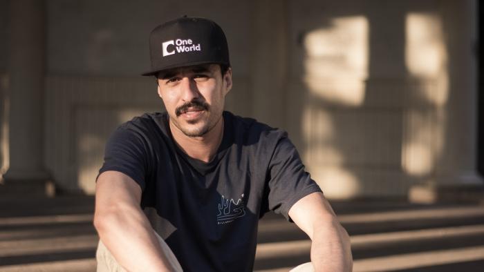 Merch Muž s kšiltovkou sedí venku na zemi.